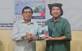 Taufik Abriansyah saat menyerahkan buku Gowes ke Merauke kepada Ketua Umum PWI Pusat