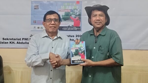 Taufik Abriansyah saat menyerahkan buku Gowes ke Merauke kepada Ketua Umum PWI Pusat