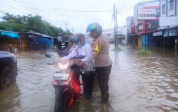 Polisi membantu warga melintasi banjir rob di Jalan Pawan 1 Ketapang.