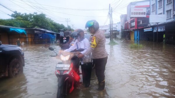Polisi membantu warga melintasi banjir rob di Jalan Pawan 1 Ketapang.