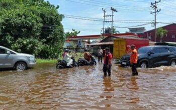 Polisi dan BPBD membantu warga melintasi genangan pasang di Ketapang.