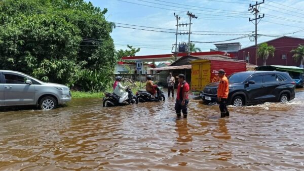 Polisi dan BPBD membantu warga melintasi genangan pasang di Ketapang.
