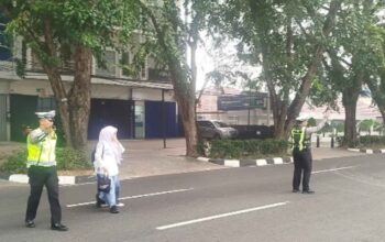Polisi lalu lintas Polda Kalbar membantu anak sekolah menyeberang jalan di Pontianak.