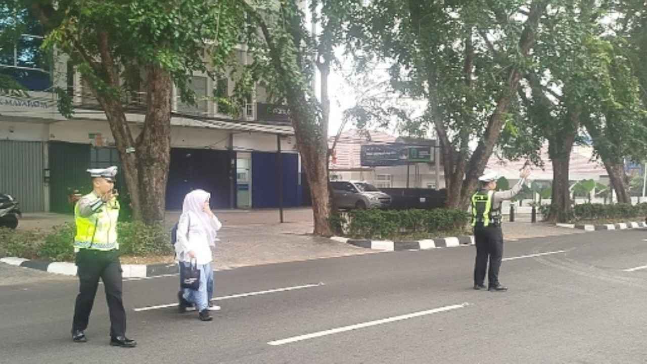 Polisi lalu lintas Polda Kalbar membantu anak sekolah menyeberang jalan di Pontianak.